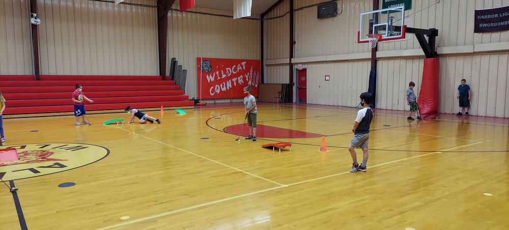 Elementary students  playing putt putt golf in gym class. 